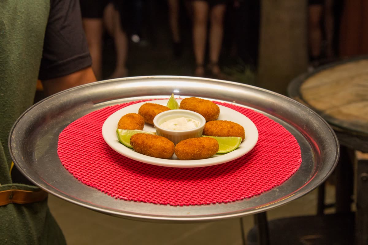 Porção de croquetes com molho e limão, servida na bandeja