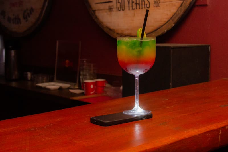 Drink colorido em taça sobre balcão de madeira